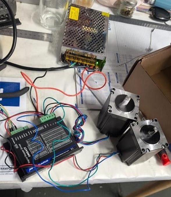 Two stepper motors, a motor driver board and a power supply on a bench